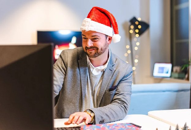 Smiling man working on a computer in a Santa hat