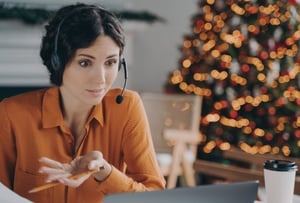 Woman speaking on a headset with a Christmas tree in the background
