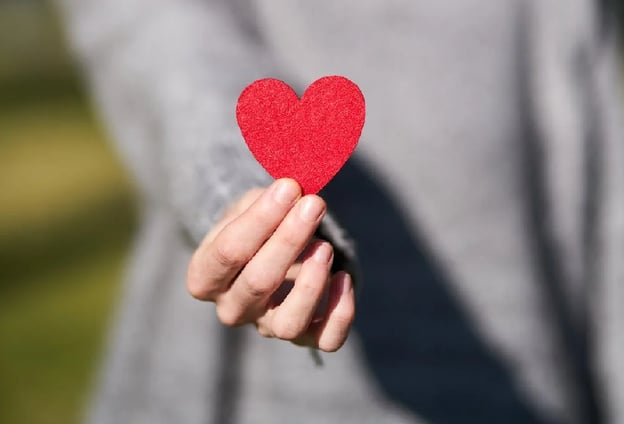 Person holding a red paper heart