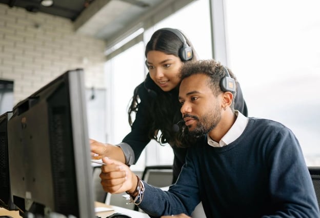 A woman mentoring a man on a computer